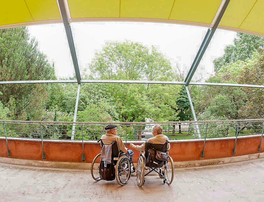 Beren gurpildun aulkietan eserita dauden egoiliar bikote bat lorategiari begira daude terrazatik