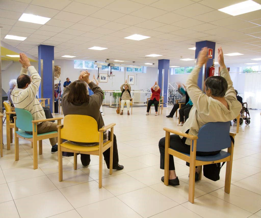 Eguneko zentroan ariketak egiten, zikuluan eserita dauden adineko pertsonak.