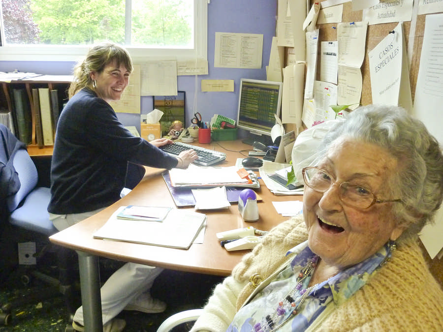  erizain batek ordenagailuaren aurrean lan egiten du, bere burua lehen planoan ikusten duen egoiliar bat artatzen duen bitartean, eta biek irribarre konplizeak egiten dituzte.