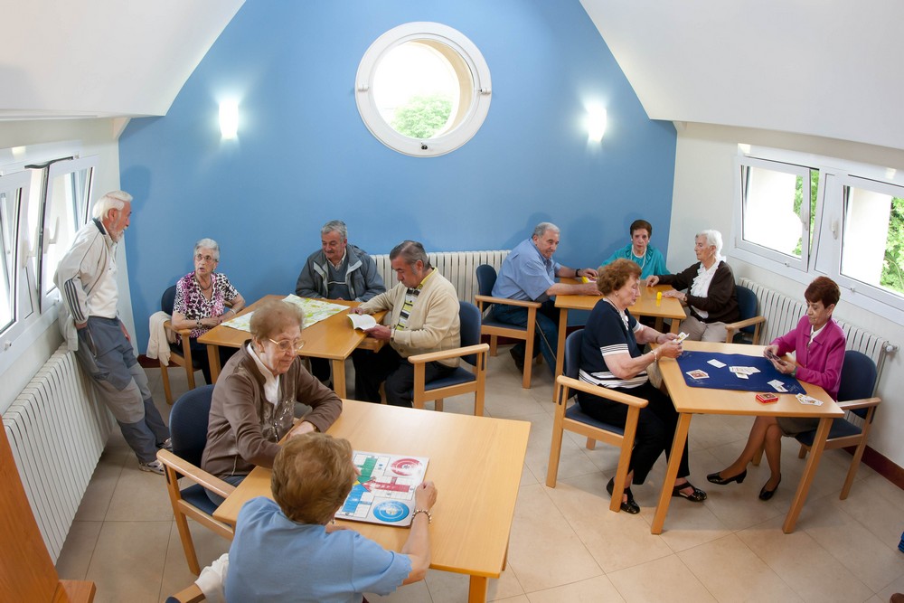  Etxebizitza komunitarioetako egongela, egoiliarrak hizketan eta jolasean.